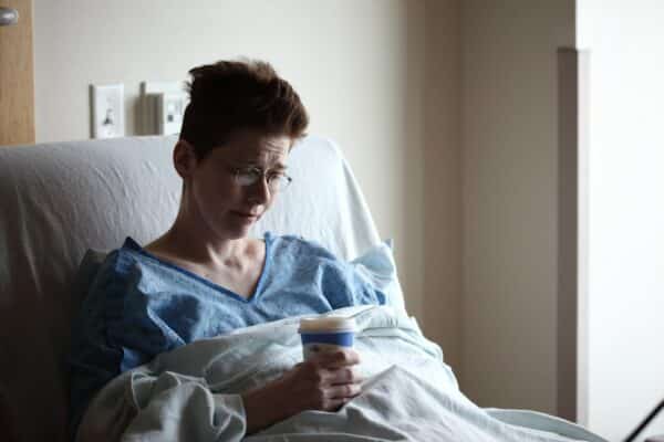 A female patient in a hospital bed looking forlorn.